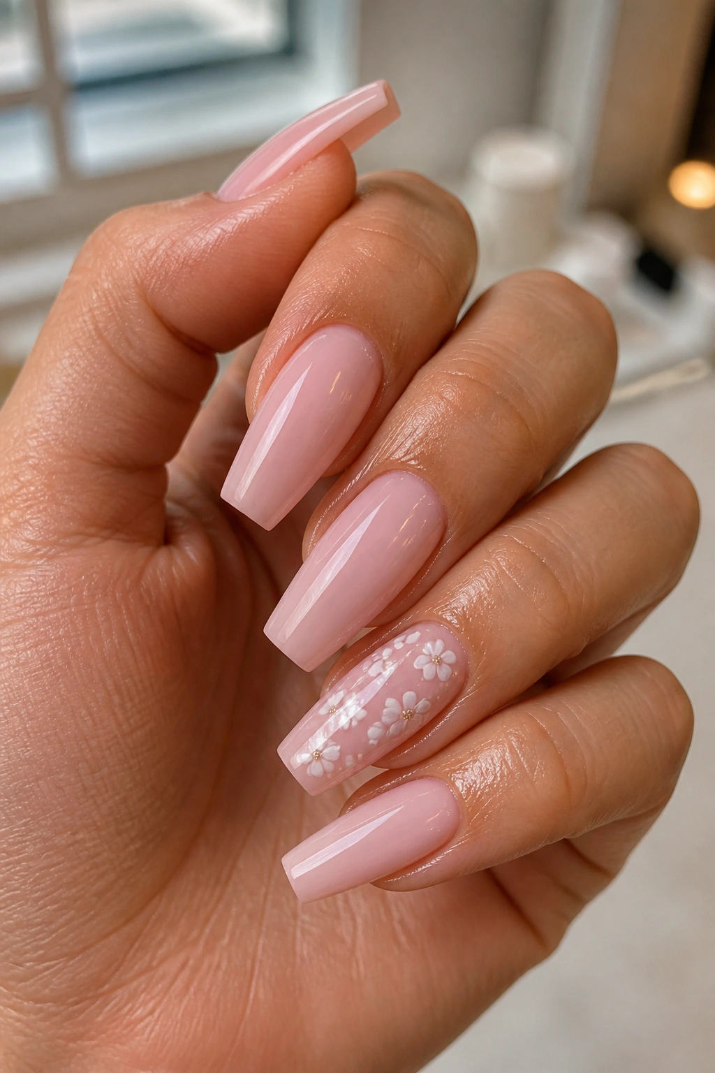 Close-up of light pink coffin nails with tiny white florals on accent nails