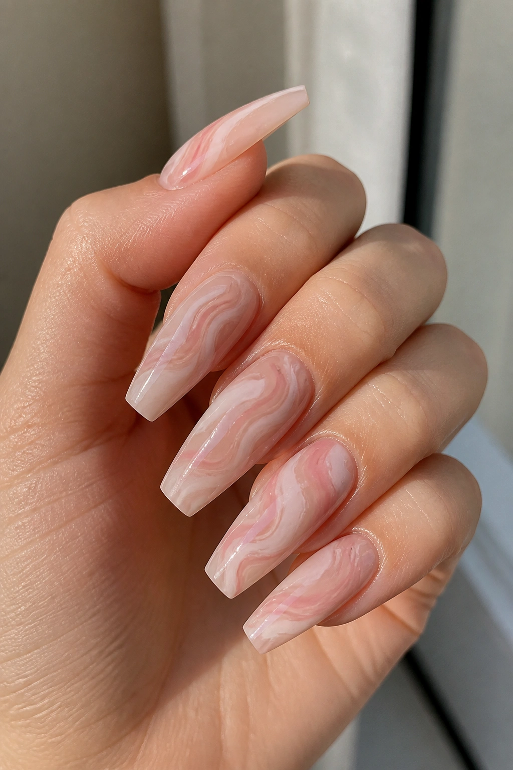 Pink nude marble swirl coffin nails on a real hand