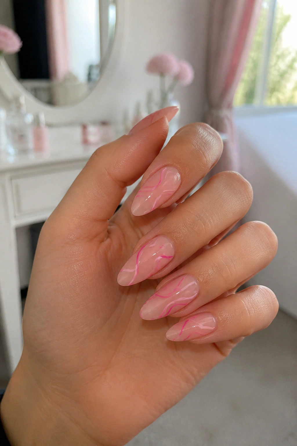 Close-up of almond nails with pink swirl art on a real hand