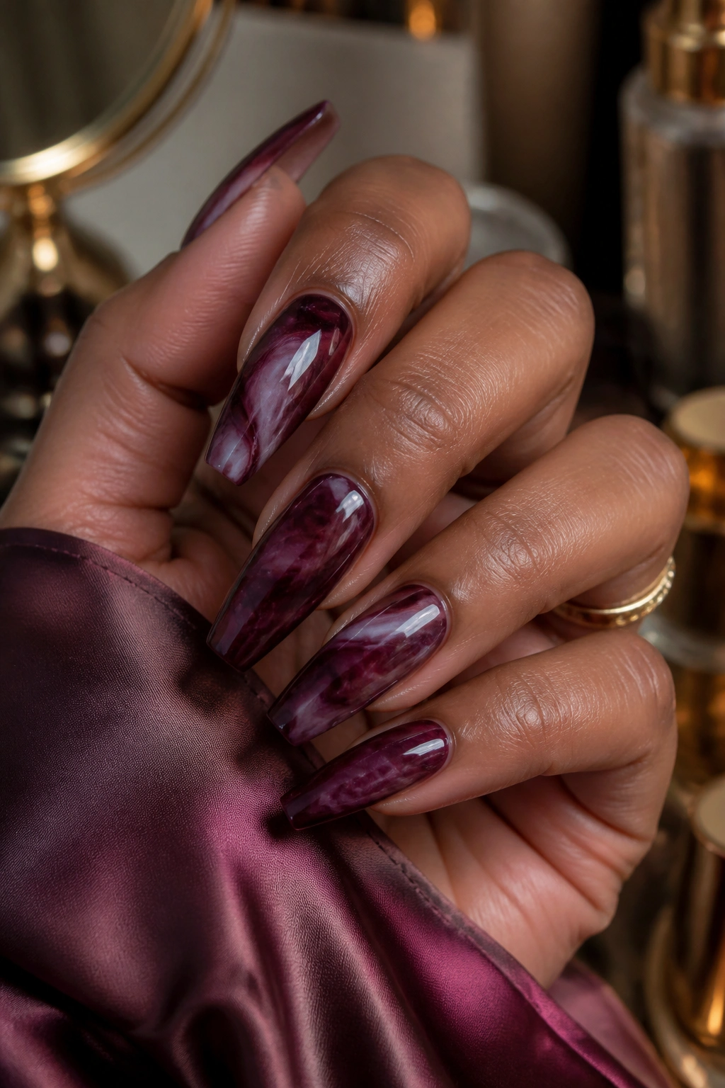 Close-up of plum-burgundy marble coffin nails on real hand