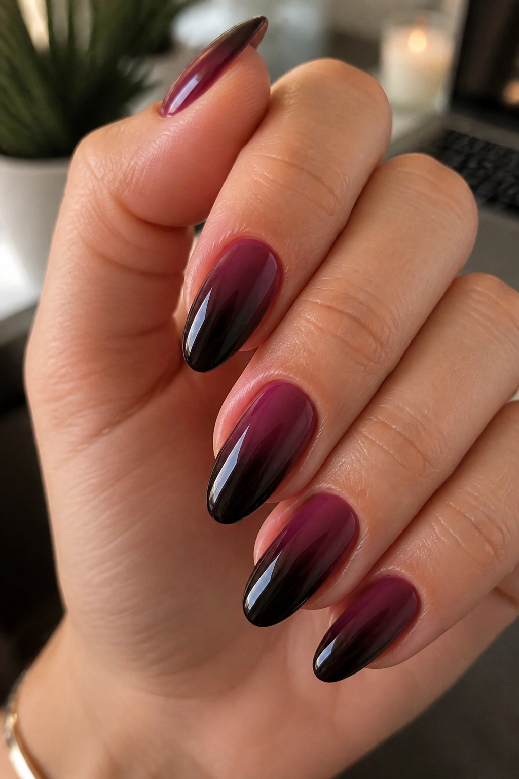 Close-up of almond nails with plum to black ombre and glossy shine