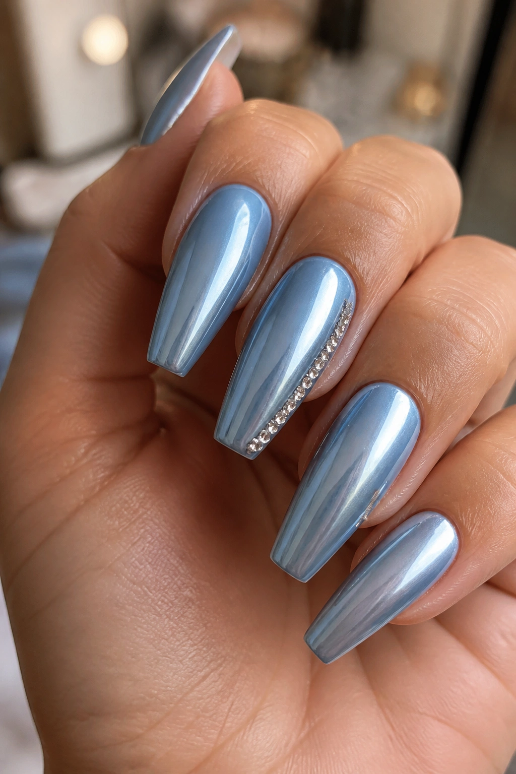 Close-up of powder-blue chrome coffin nails with a delicate crystal side line on a real hand