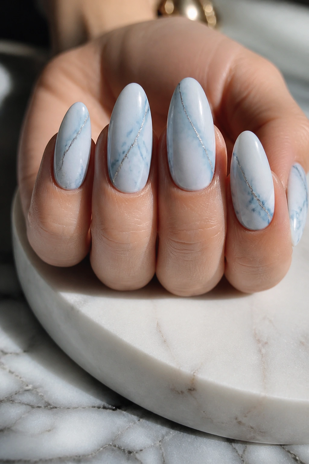 Almond nails with powder blue marble pattern and silver veining