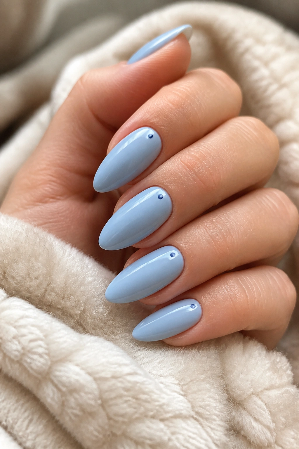 Almond nails powder blue with a single tiny dot near cuticle close-up.