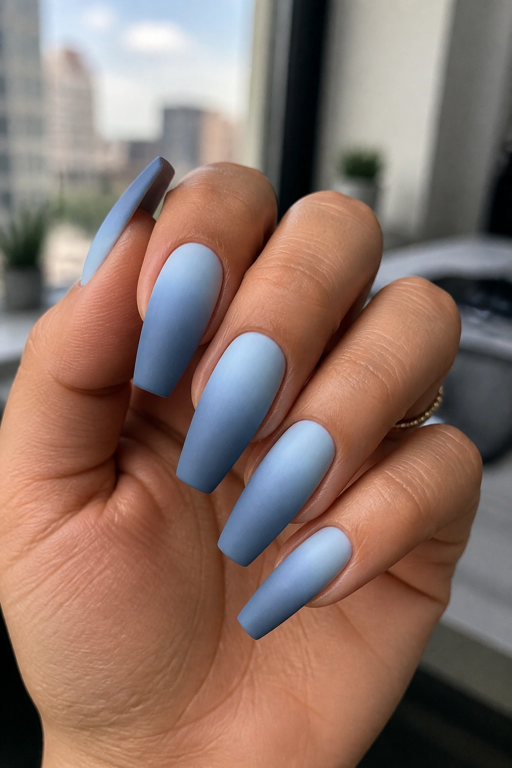 Close-up of powder blue to slate blue matte coffin nails on a real hand