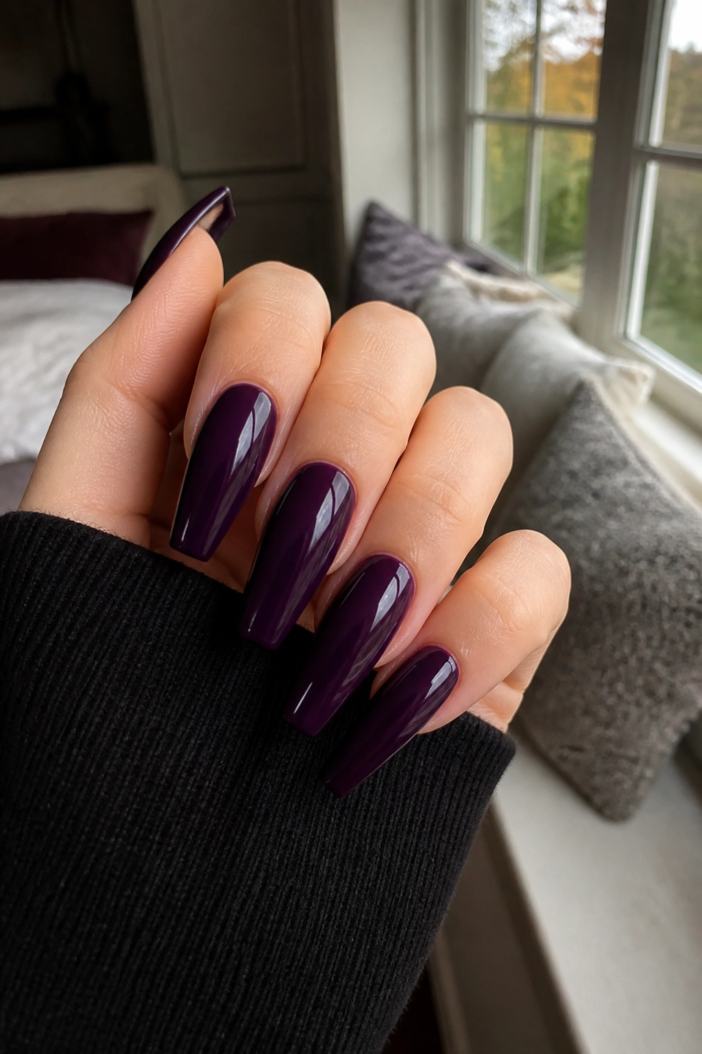 Close-up of purple coffin nails on a real hand in natural light