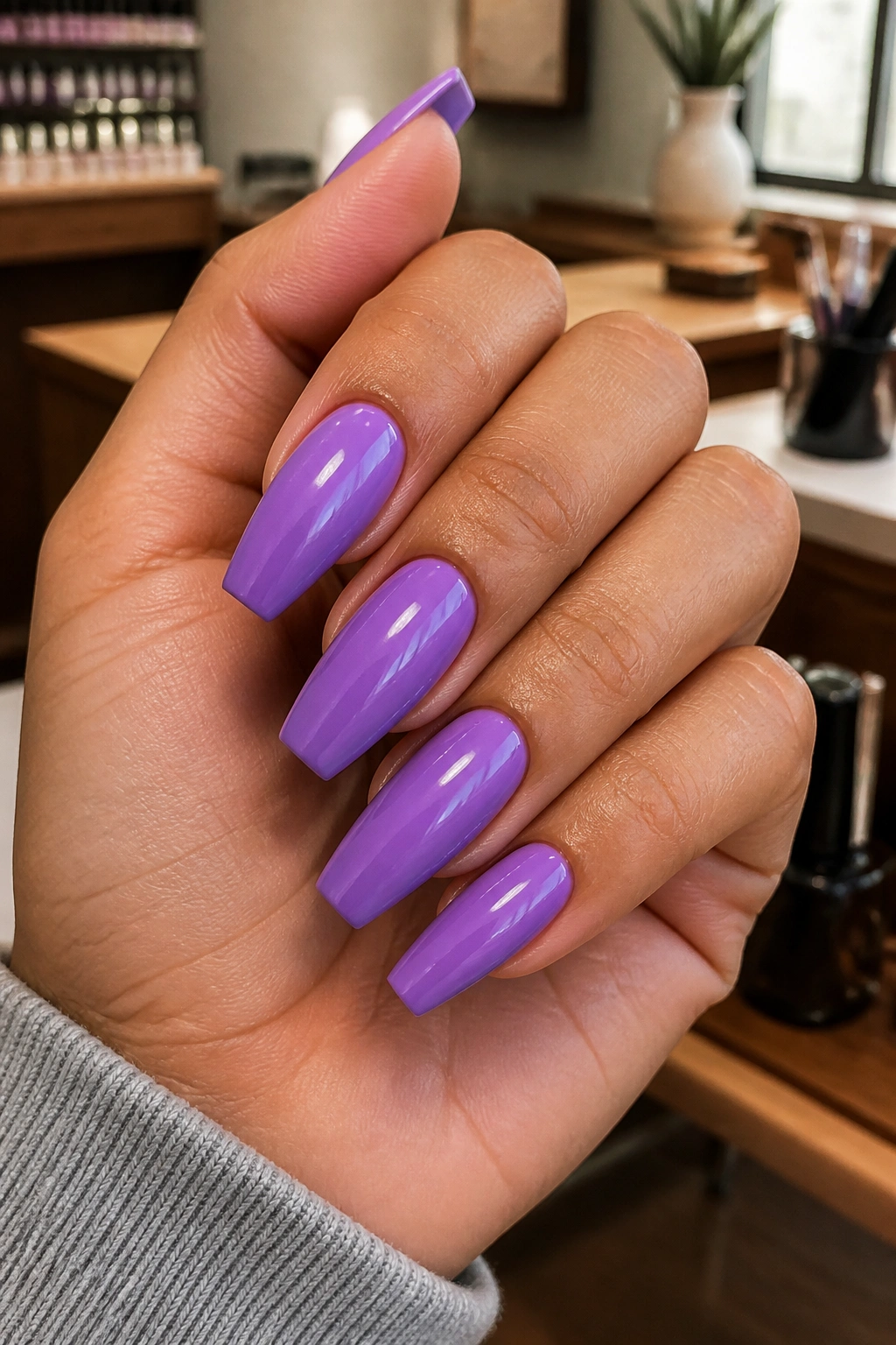 Close-up of medium-length coffin nails in lavender purple polish on a real hand, salon-like setting.