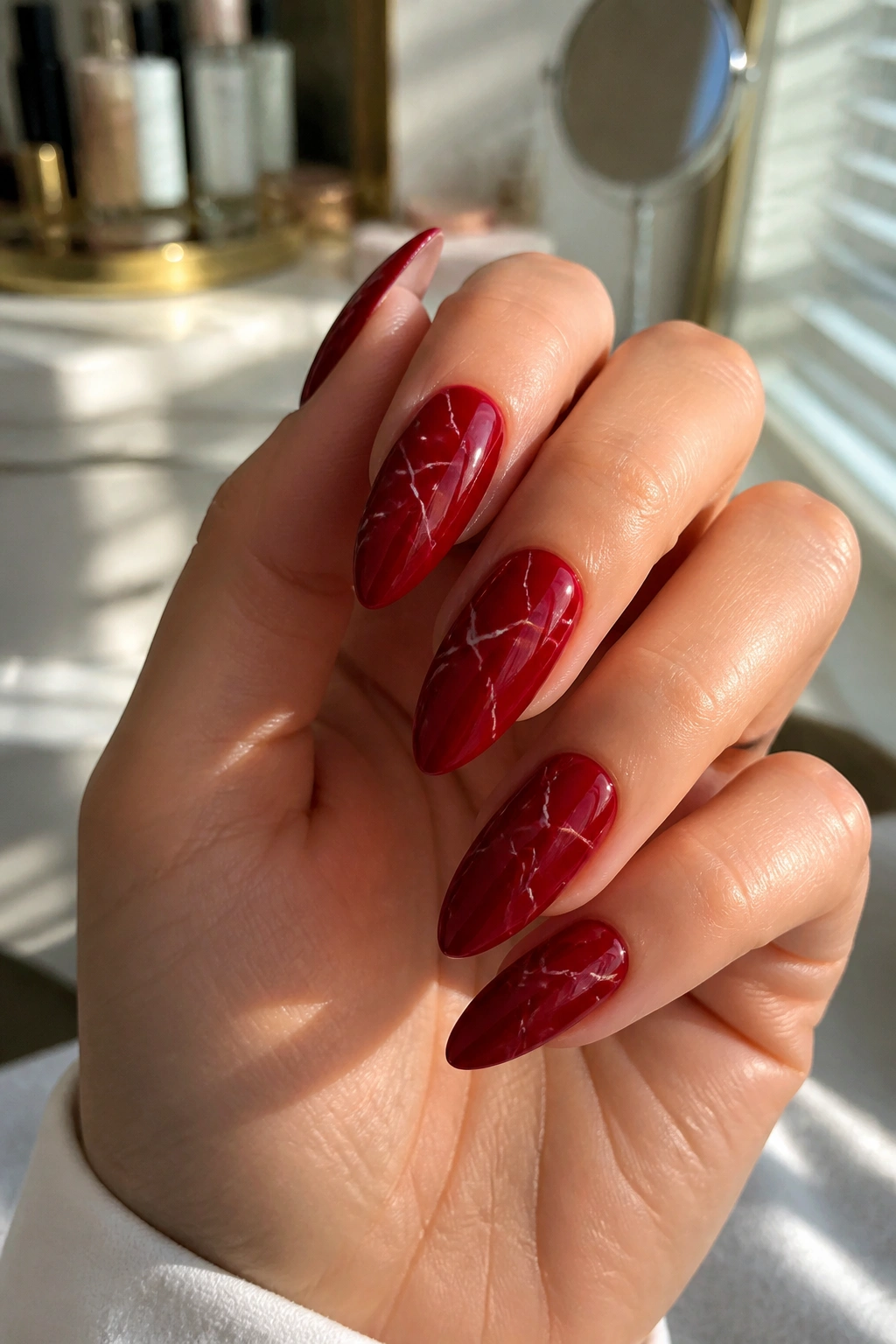 Close-up of long almond nails with red base and white marble veins on a real hand