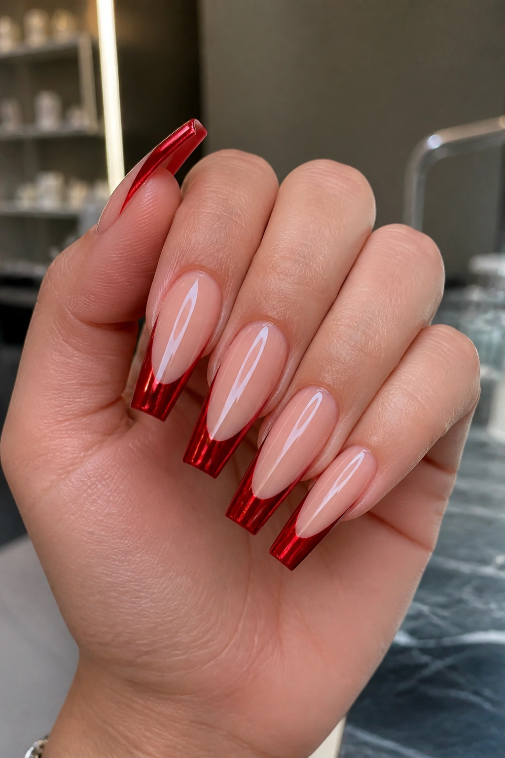 Close-up of red chrome French tips with mirror shine on coffin nails