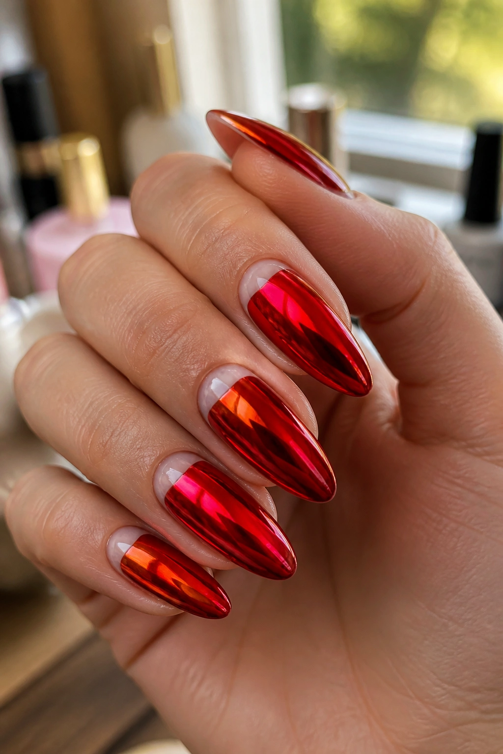 Close-up of almond-shaped red chrome nails with negative-space crescent on a real hand