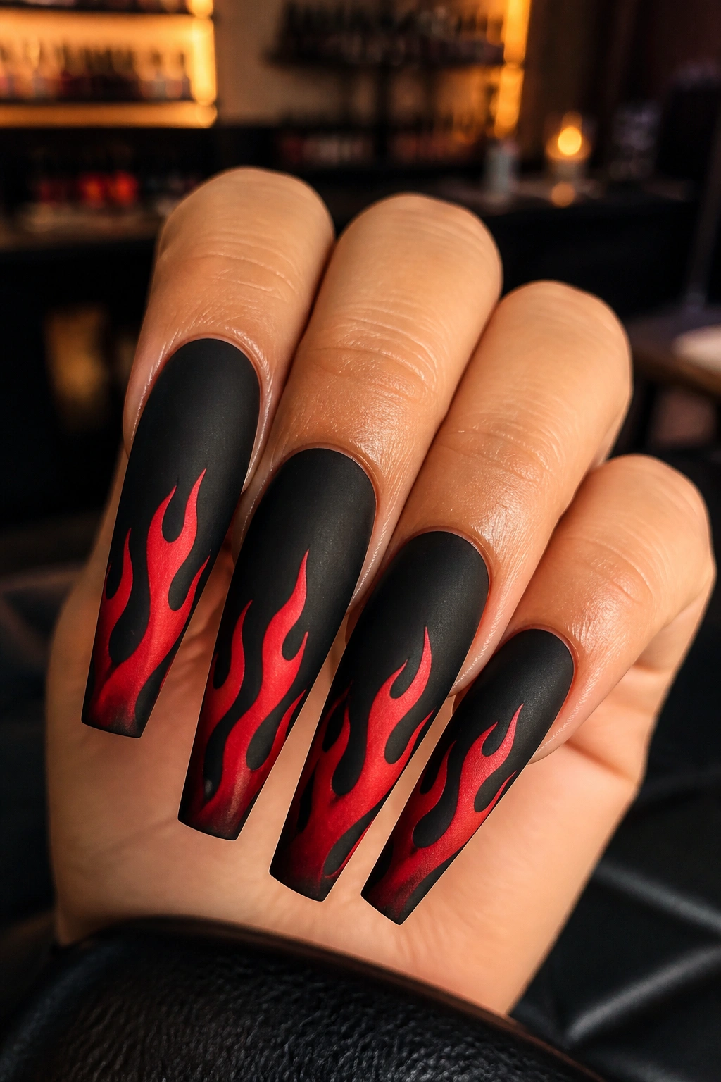 Close-up of red flame nail art on black coffin nails on a real hand in a salon