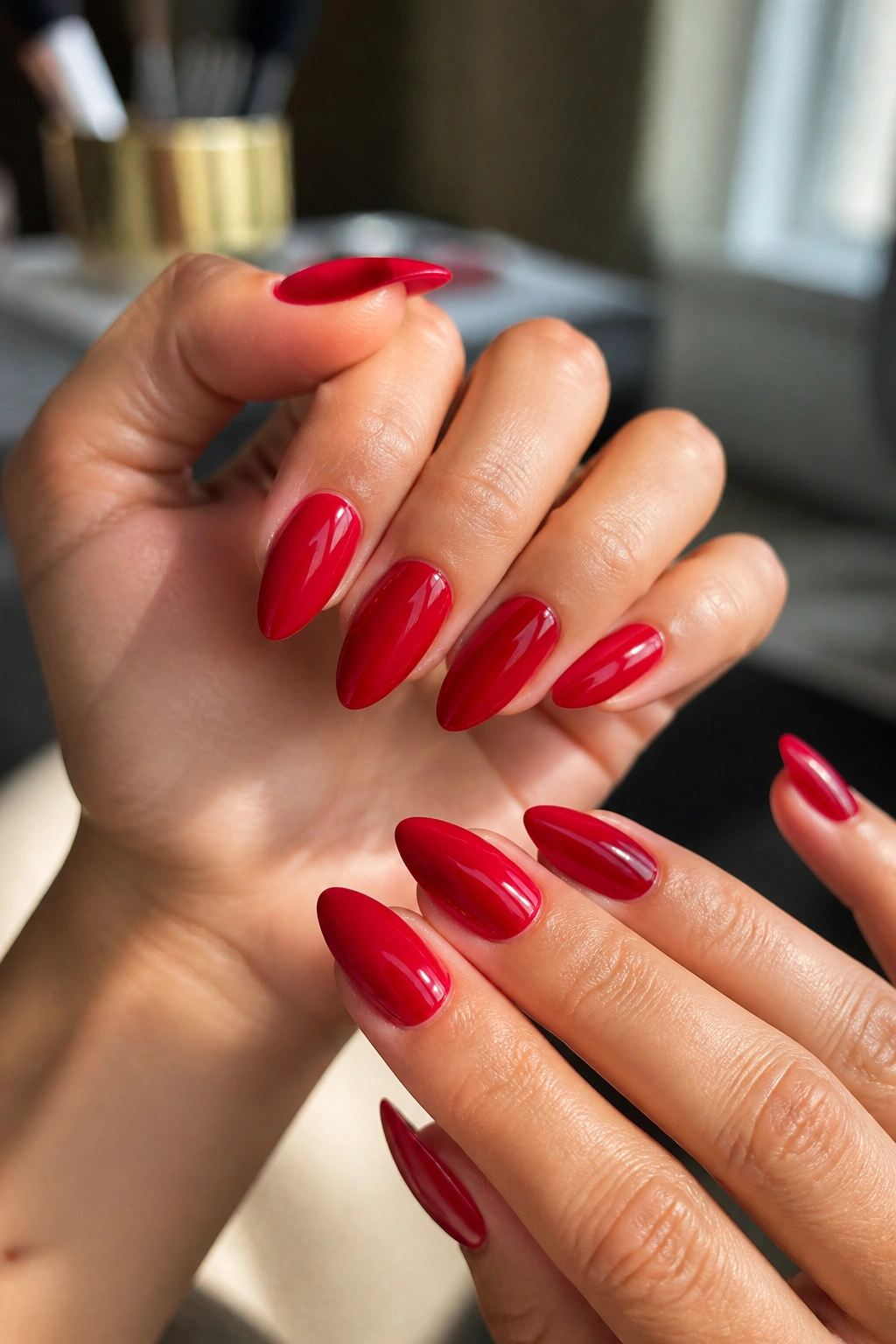Close-up of cherry-red glossy almond nails on a real hand