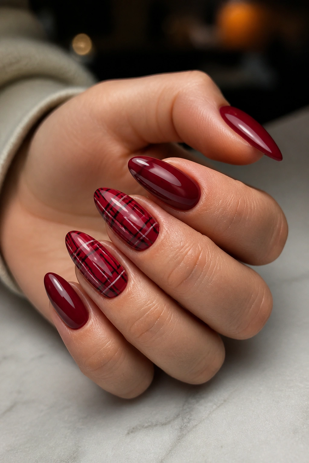 Close-up of red plaid almond nails on a real hand