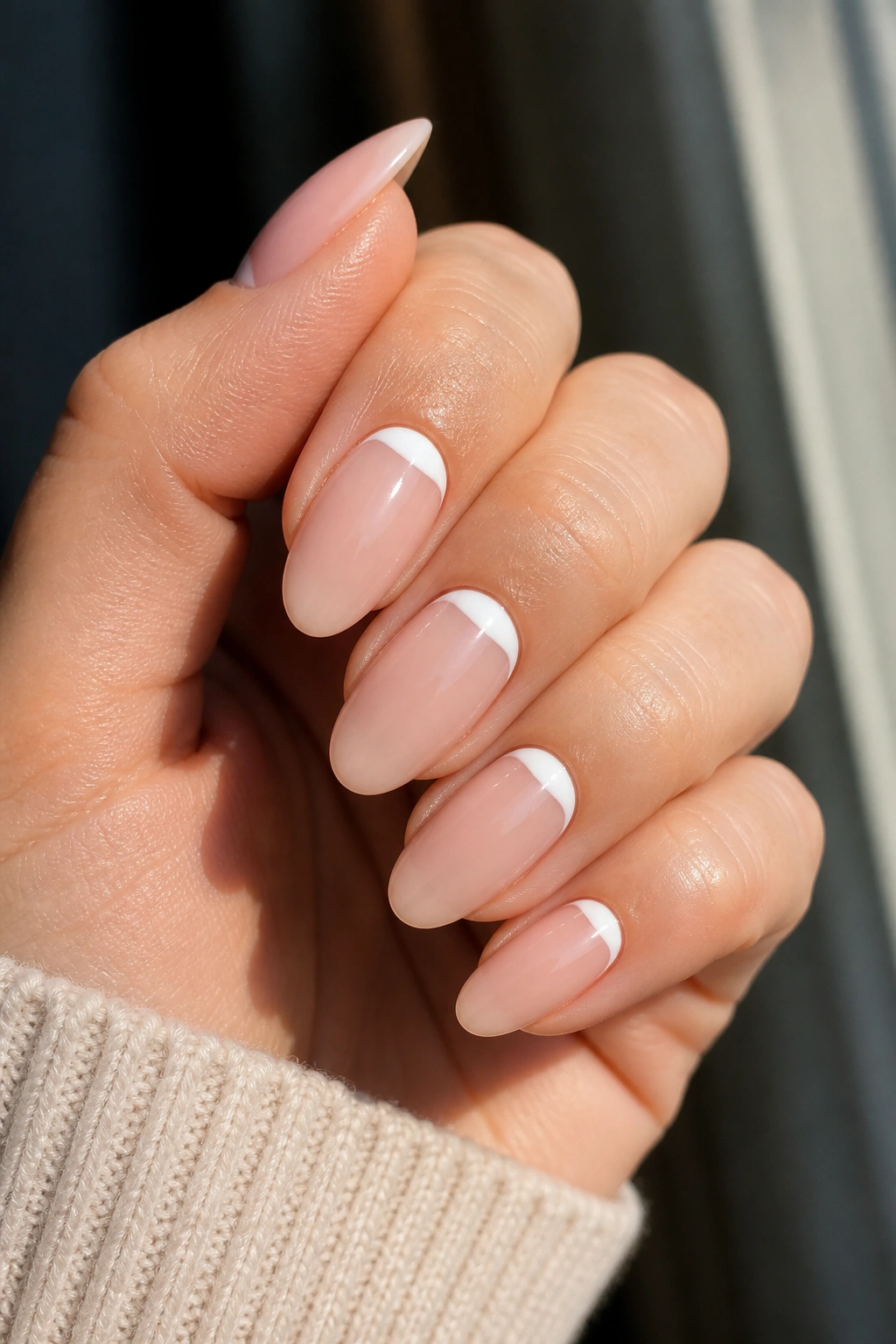 Close-up of a real hand with reverse French tips near the cuticle on almond nails
