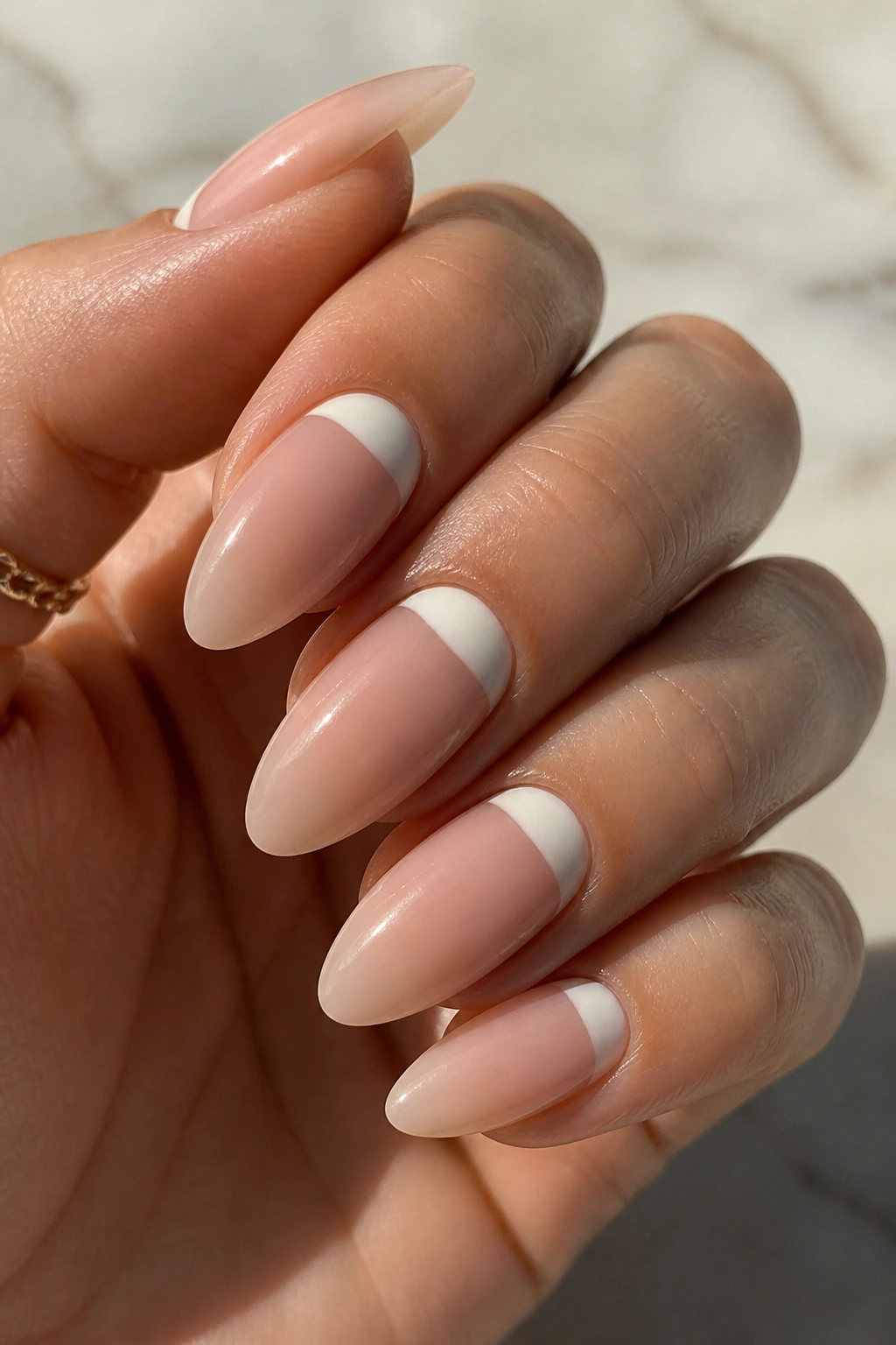 Close-up of almond nails with ivory half-moon design at the cuticle