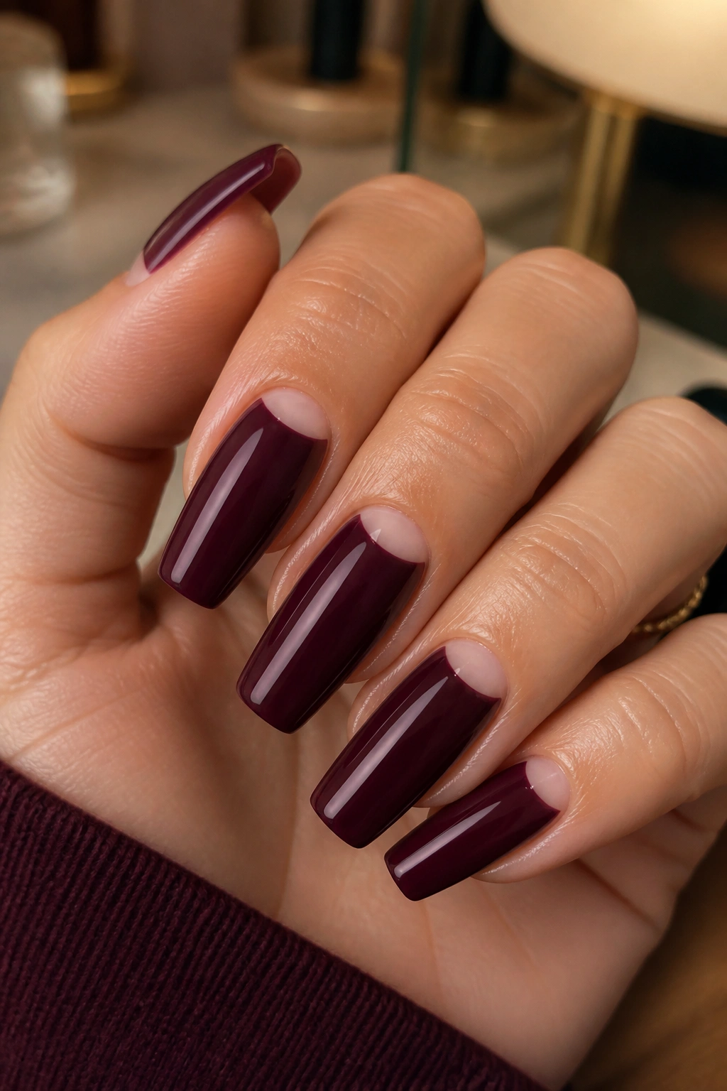Close-up of deep wine reverse French half-moon coffin nails on a real hand