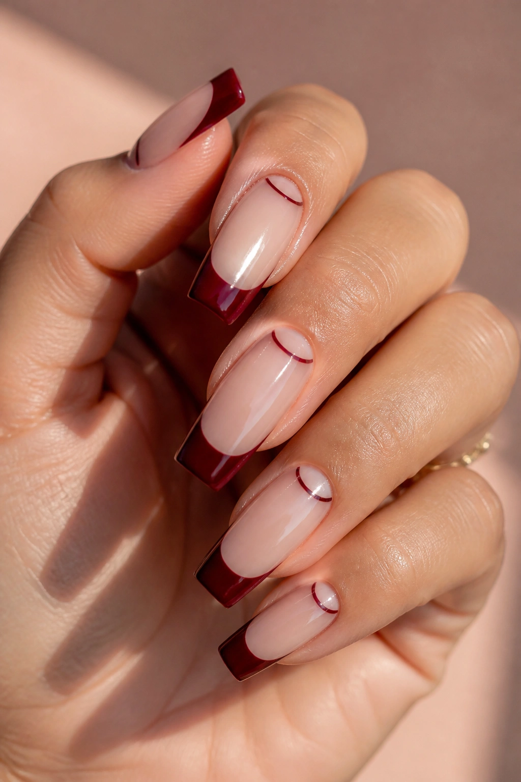 Close-up of real hand showing reverse half-moon and dark red tip nails on coffin shape.