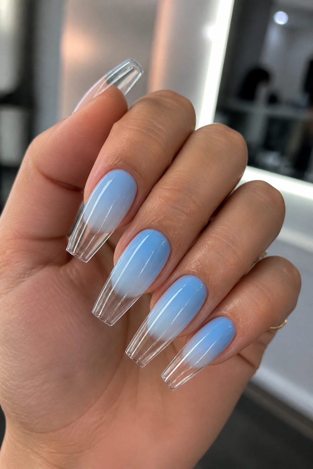 Close-up of reverse blue ombre with glassy clear tips on a real hand