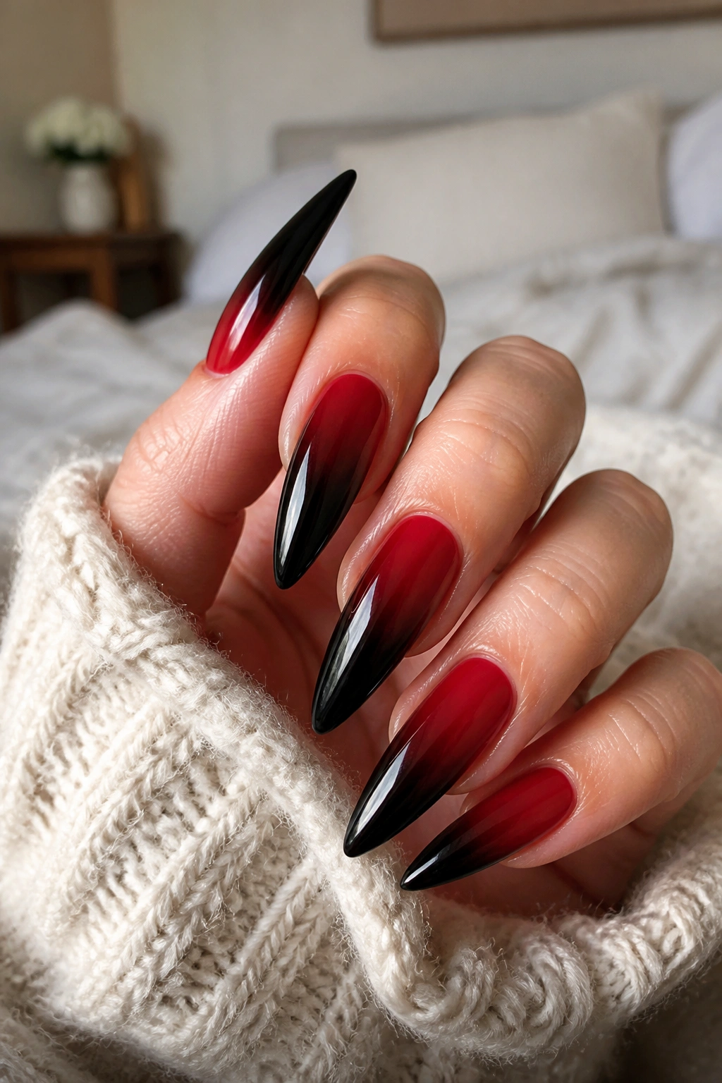 Close-up of hand with reverse ombre nails from black tips to red base.