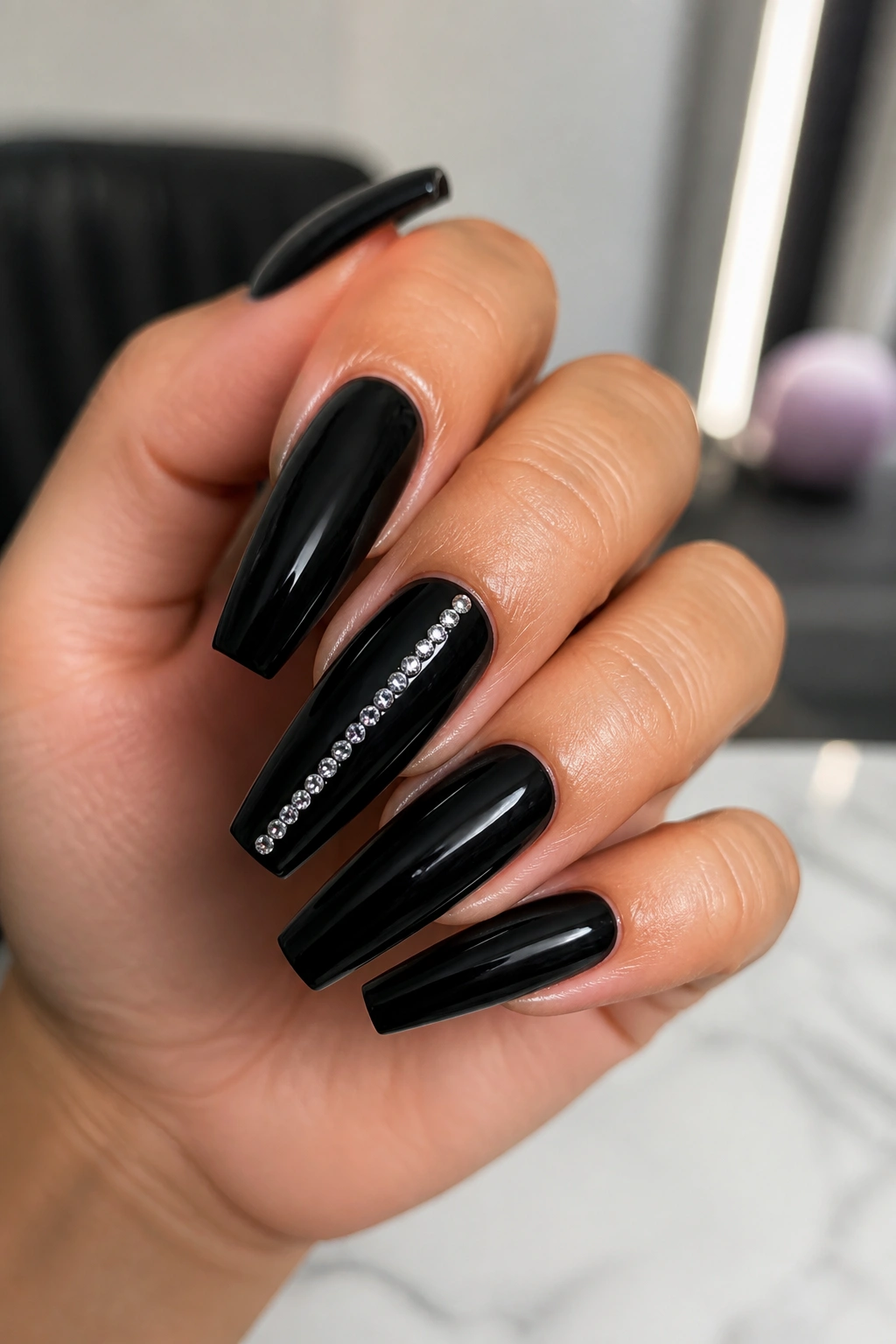 Close-up of black coffin nails with rhinestone spine on real hand