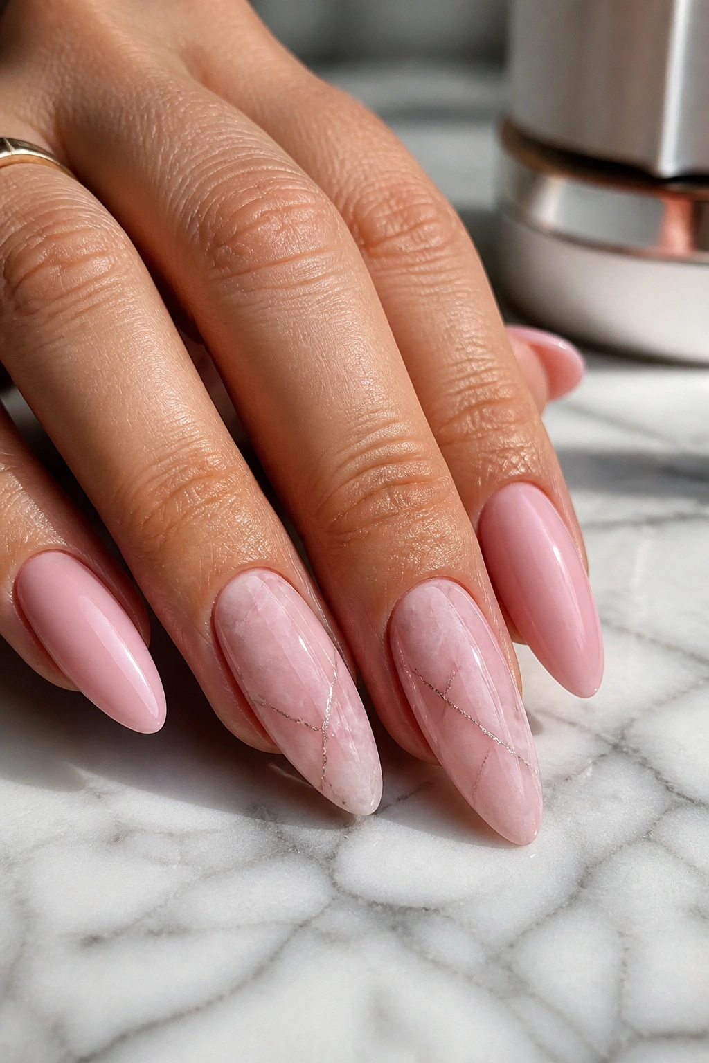 Close-up of a real hand with rose quartz marble nails on long almond nails