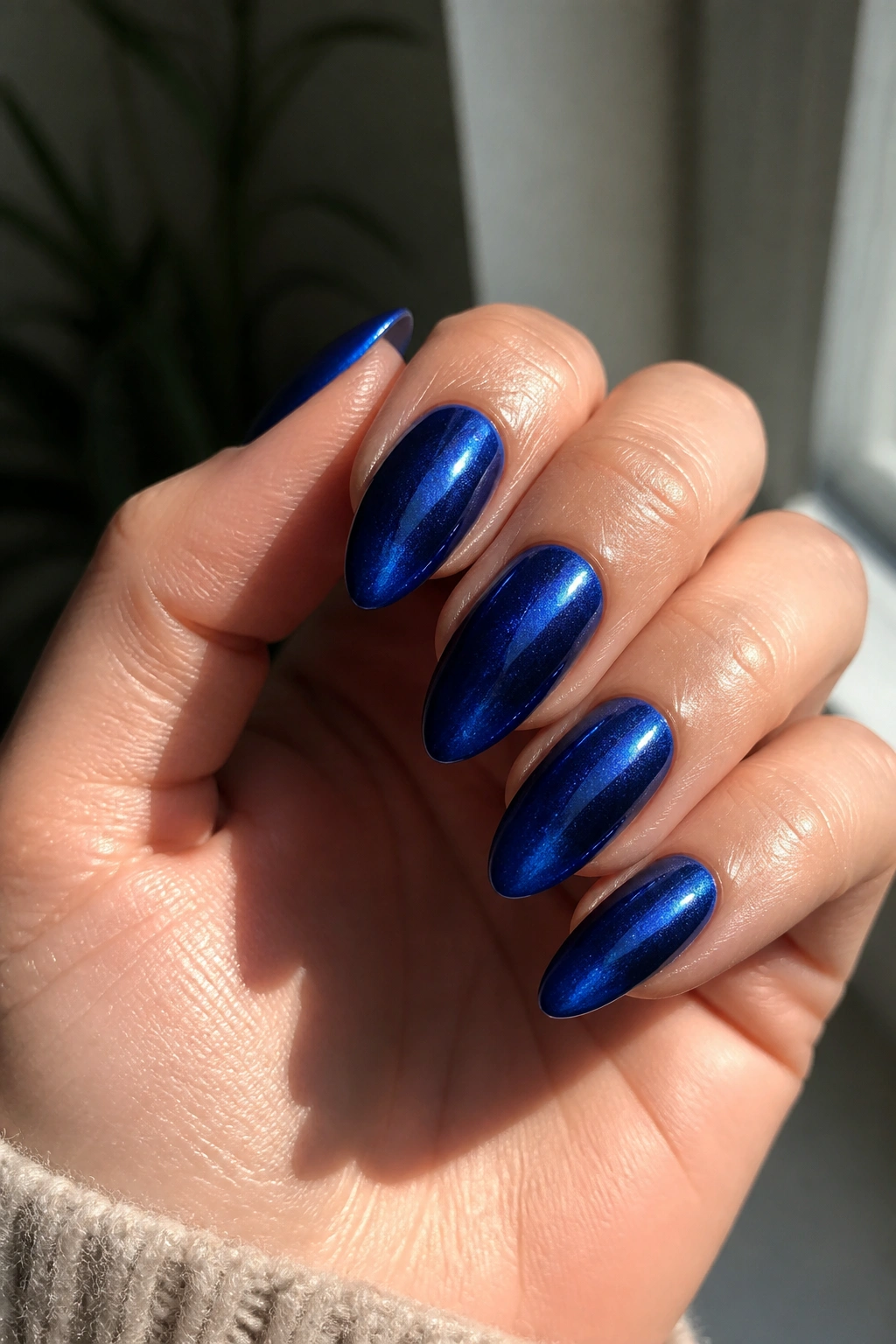 Almond nails with royal blue cat-eye effect and magnetic shimmer on a real hand