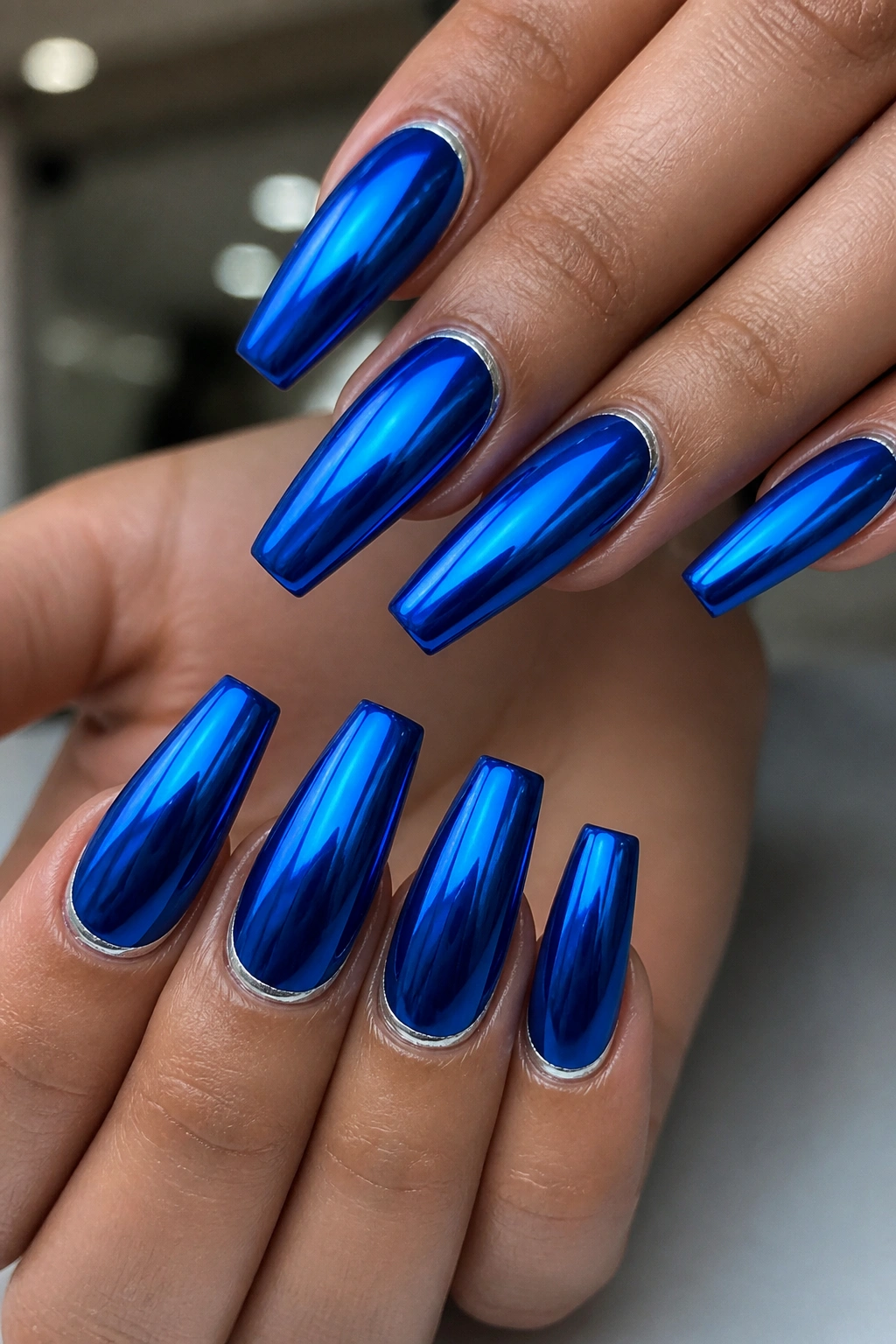 Close-up of royal blue chrome coffin nails with silver cuticle line.