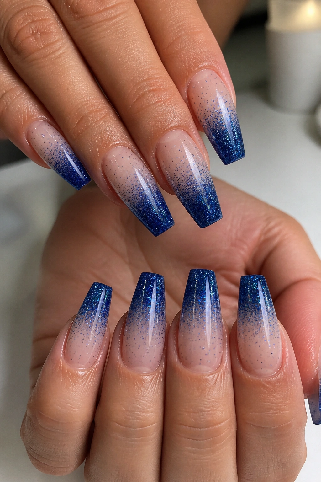 Close-up of coffin nails with sapphire glitter dip ombre on a real hand