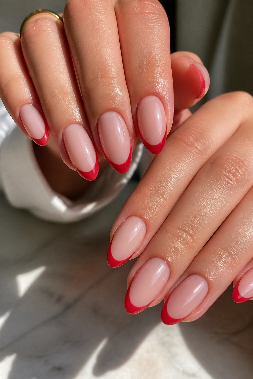 Close-up of almond nails with red tips on nude base