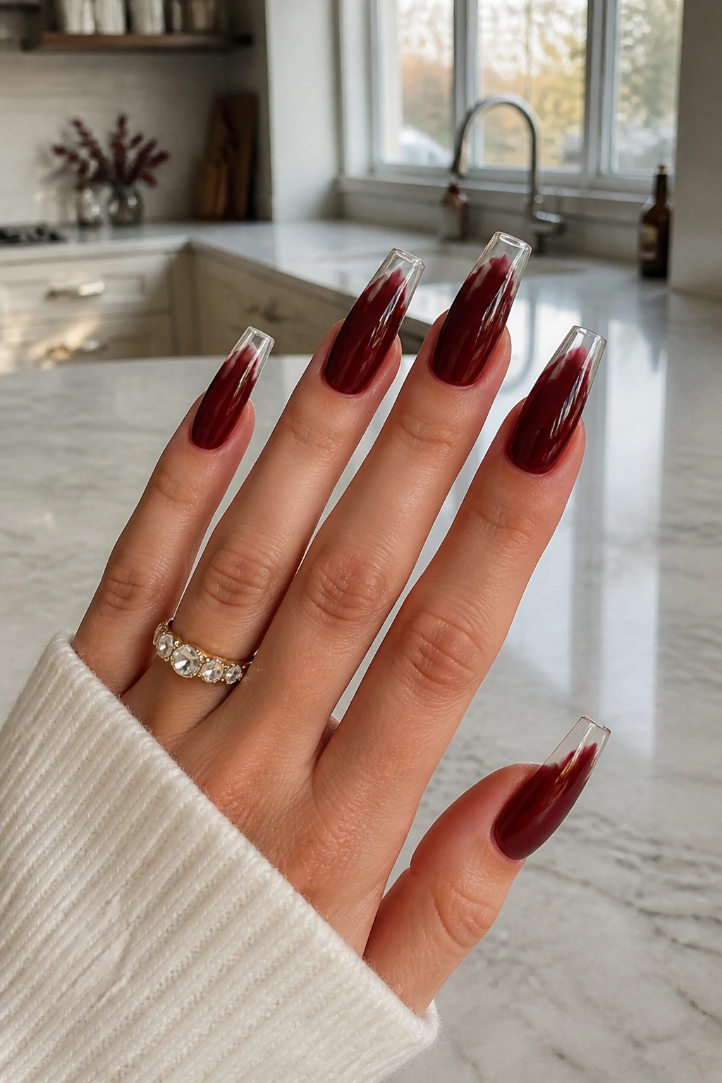 Sheer burgundy coffin nails with transparent tips on a real hand