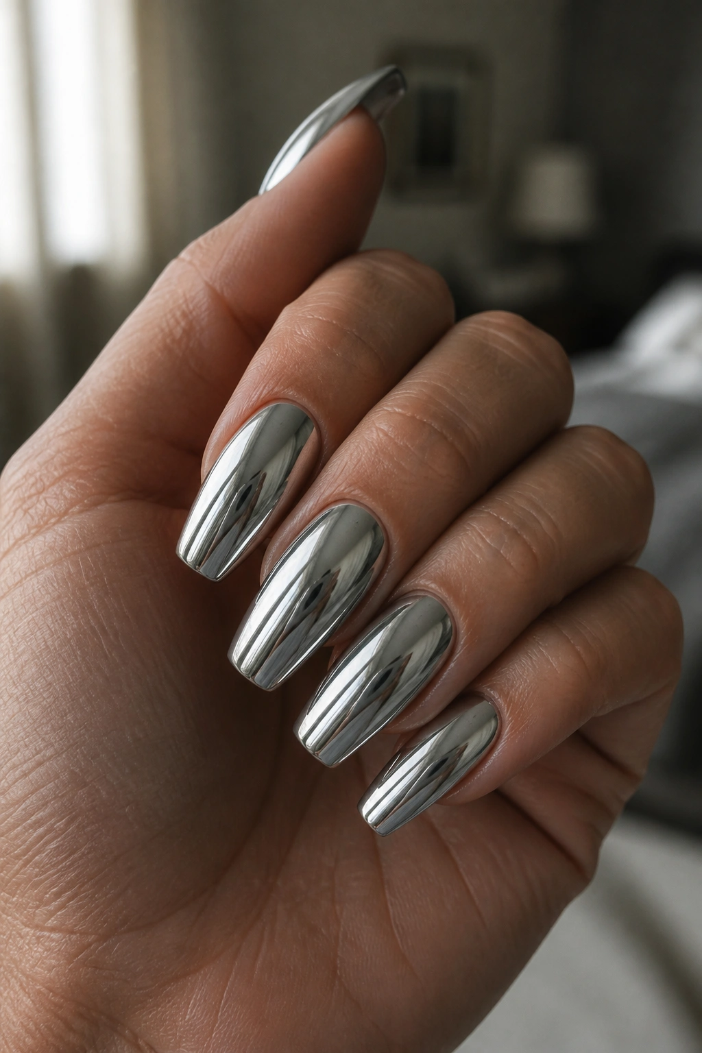 Close-up of a real hand with silver chrome coffin nails reflecting light