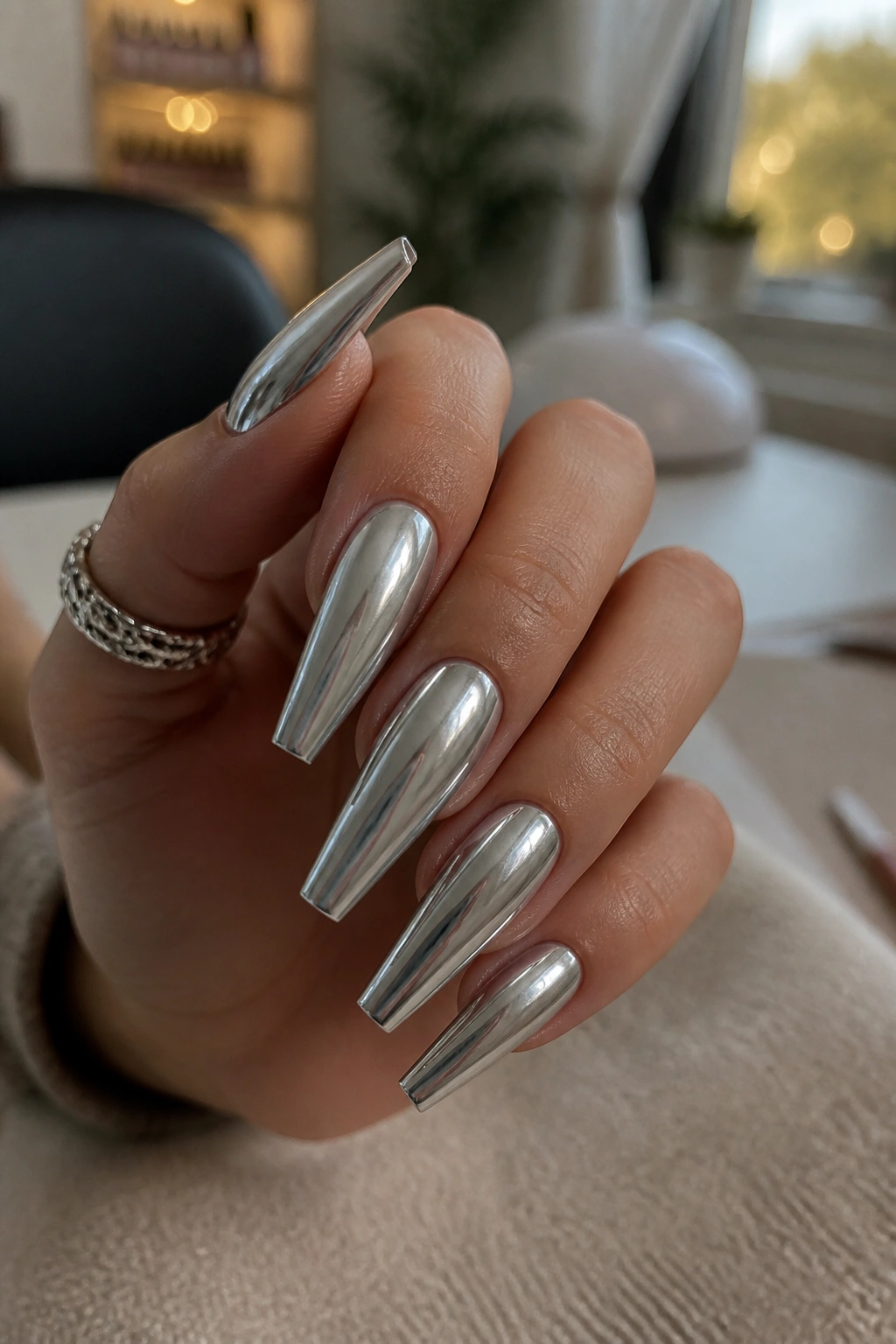Close-up of a real hand with silver coffin nails in a salon setting