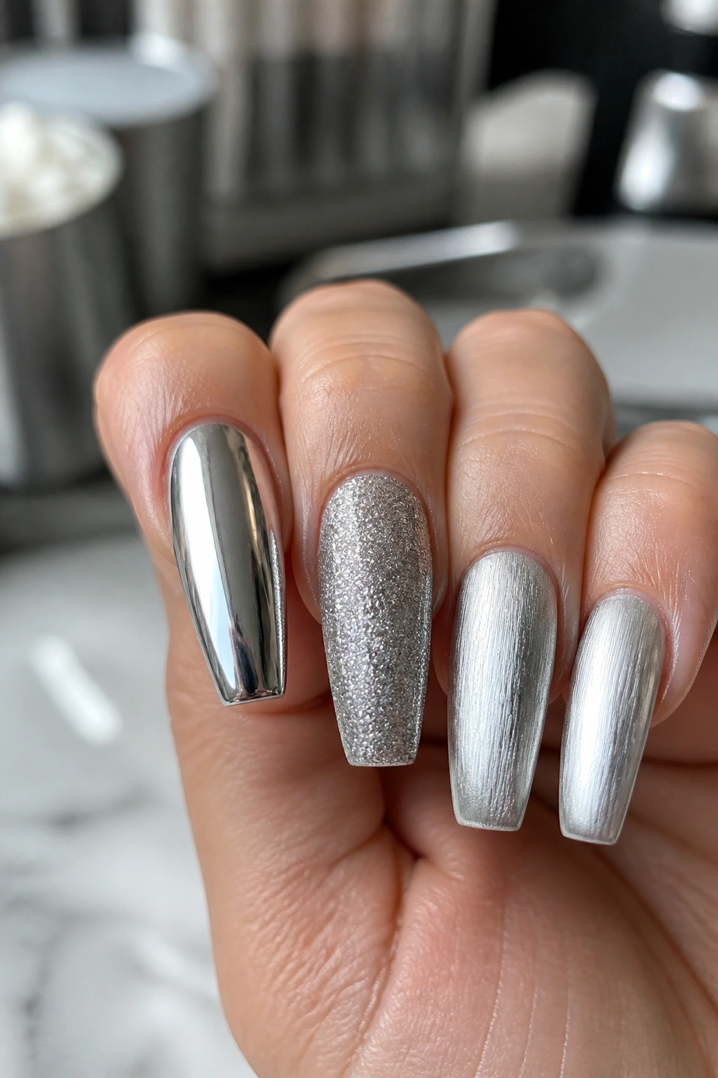 Close-up of a hand with coffin nails displaying several silver finishes