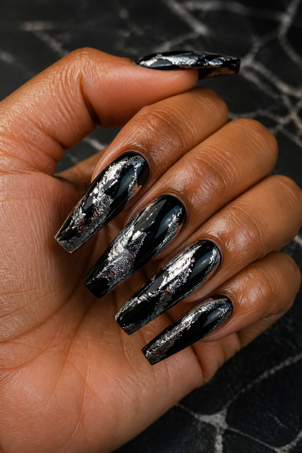 Close-up of black coffin nails with silver foil cracks.