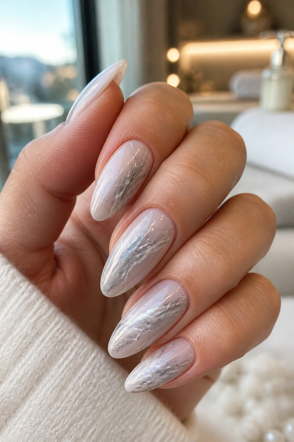 Close-up of almond nails with silver marble and white veins
