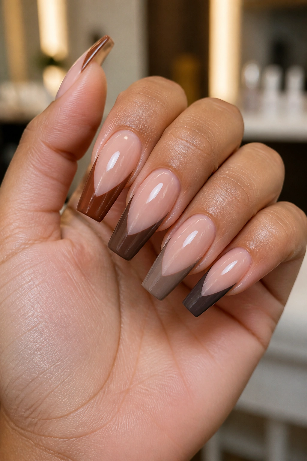 Hand with coffin nails in three brown shades to demonstrate color selection for skin tone and nail length