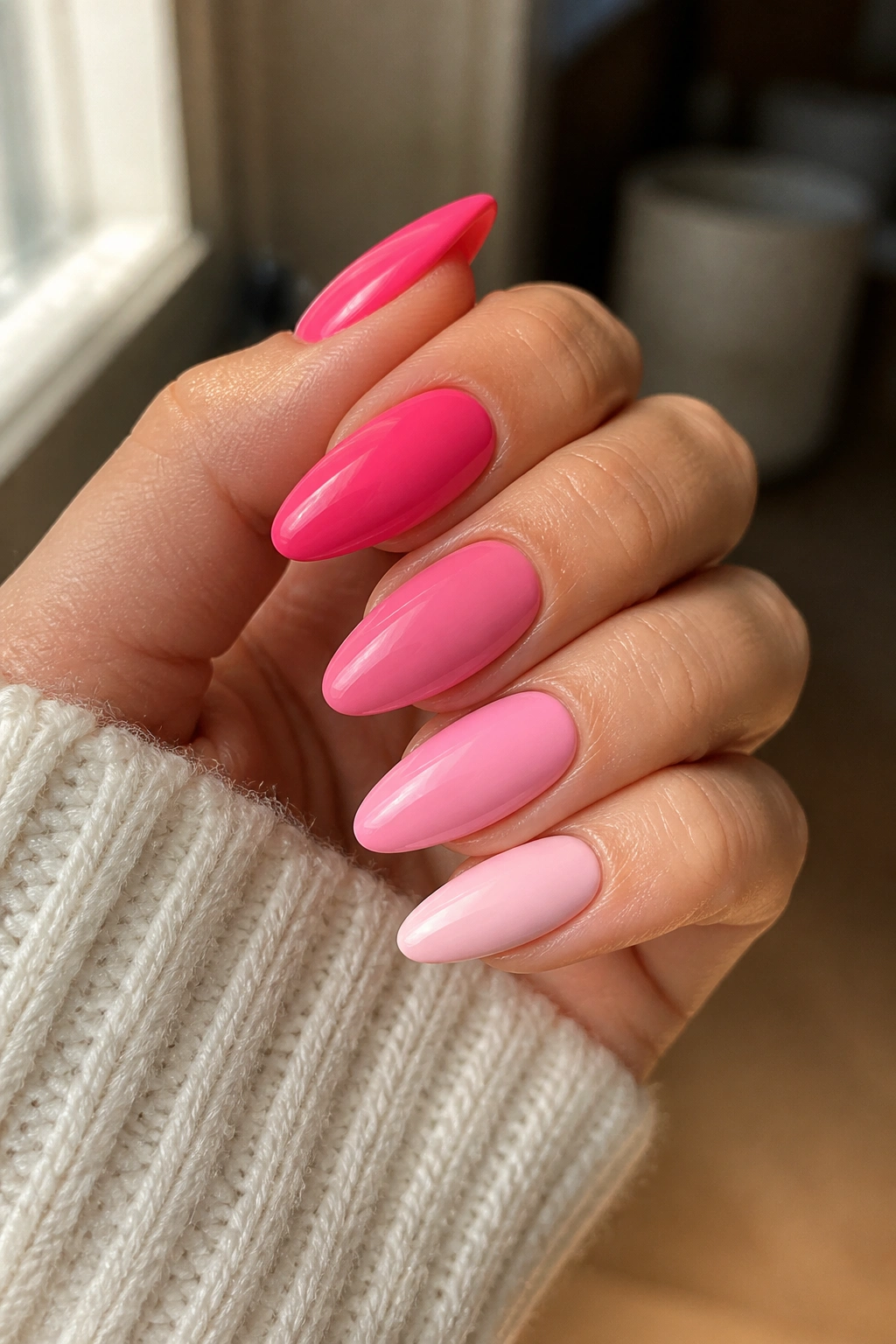 Five almond nails in gradient pink shades from neon to pale rose
