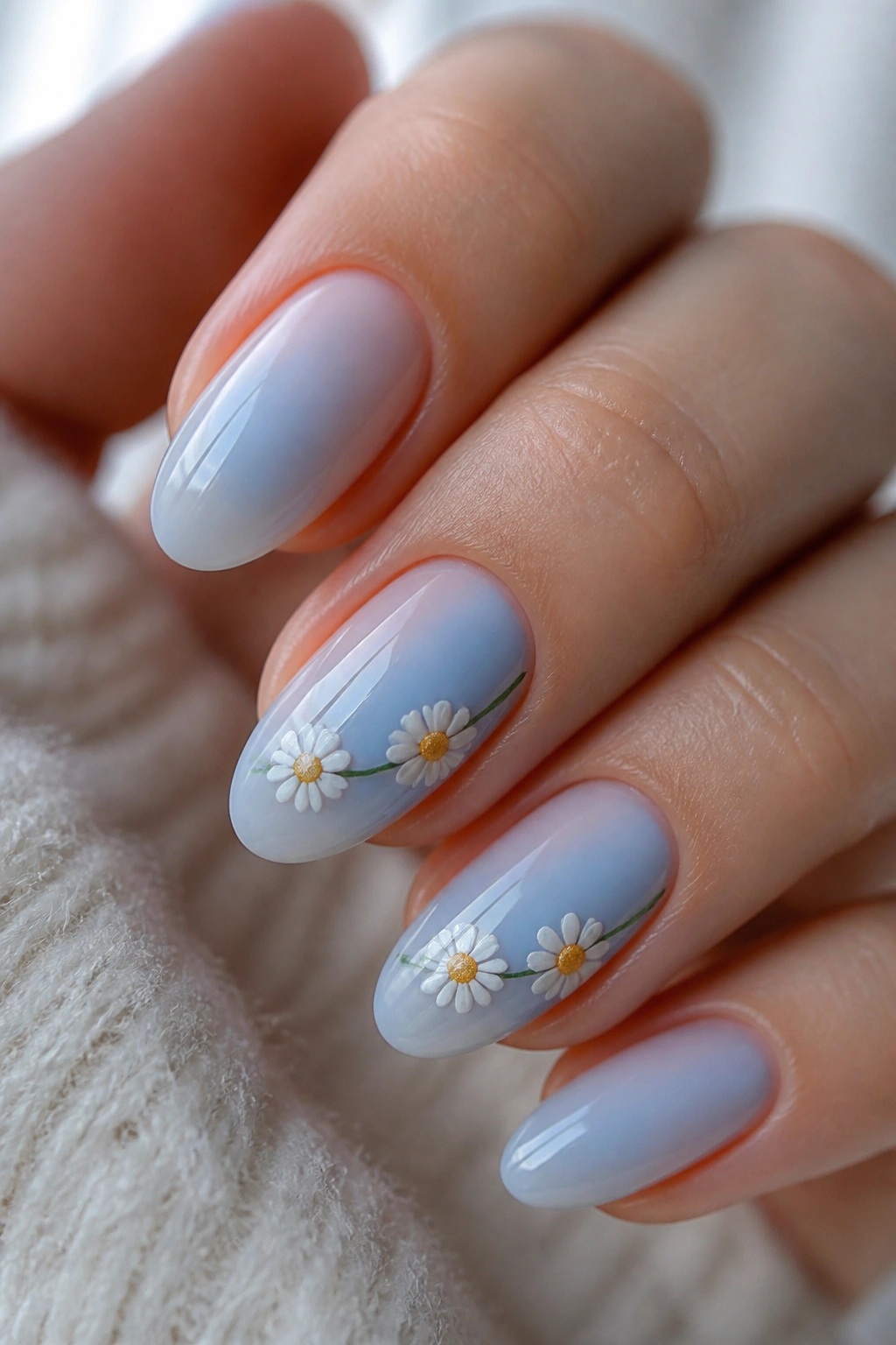 Almond nails with sky blue base and a daisy chain across two nails
