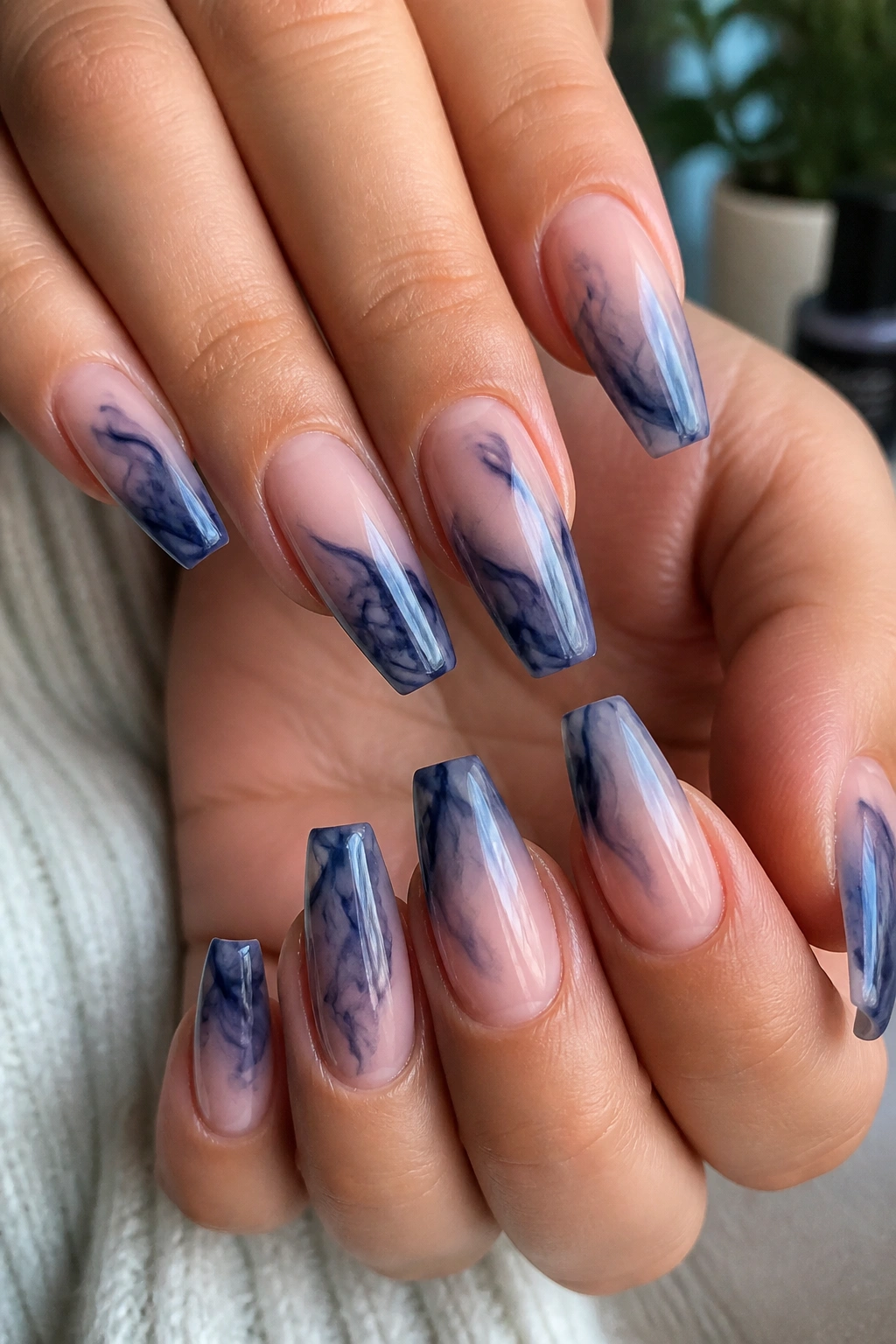 Close-up of smoked blue swirl coffin nails on a sheer base on a real hand