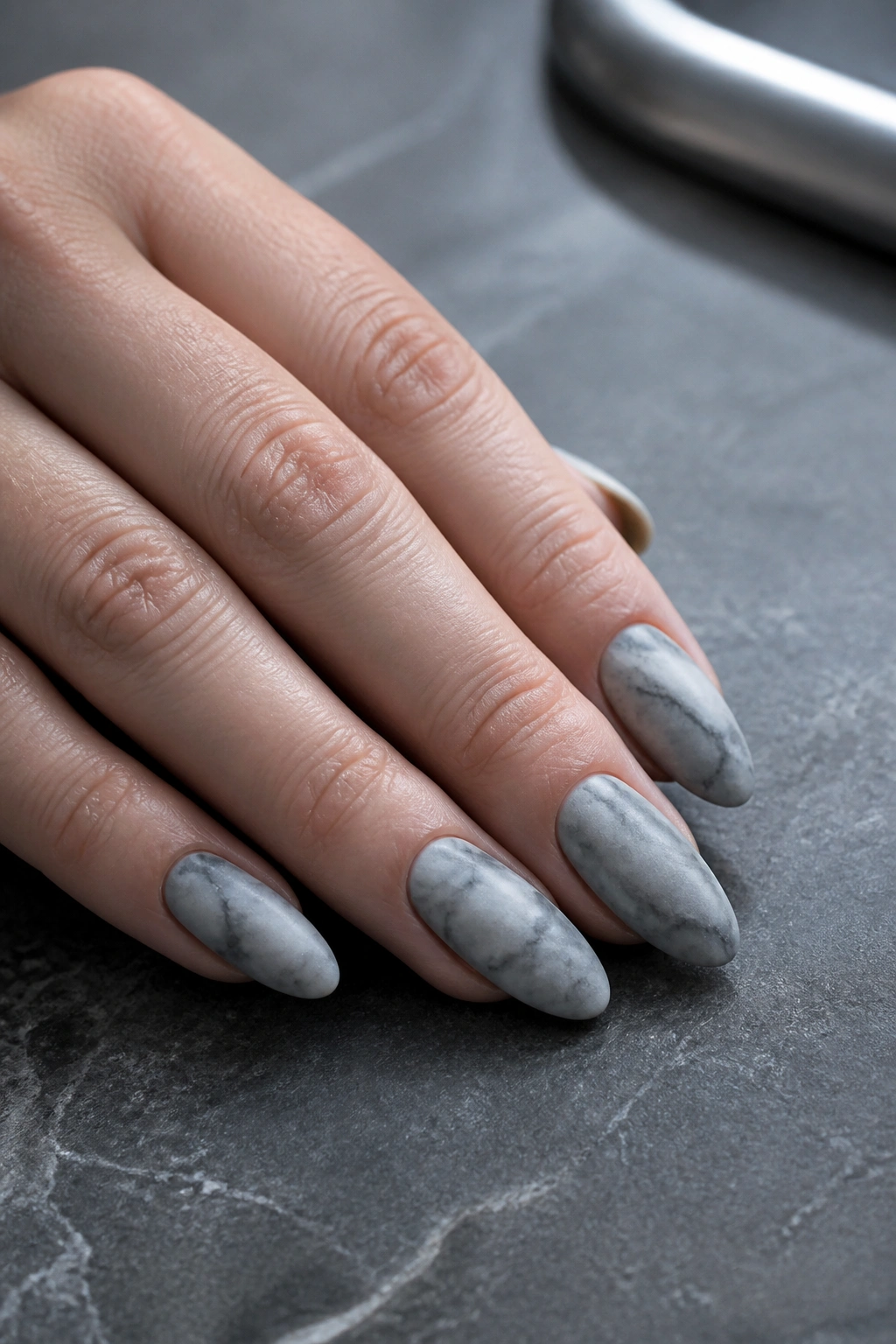 Almond nails in smoky gray marble with a matte finish on a real hand