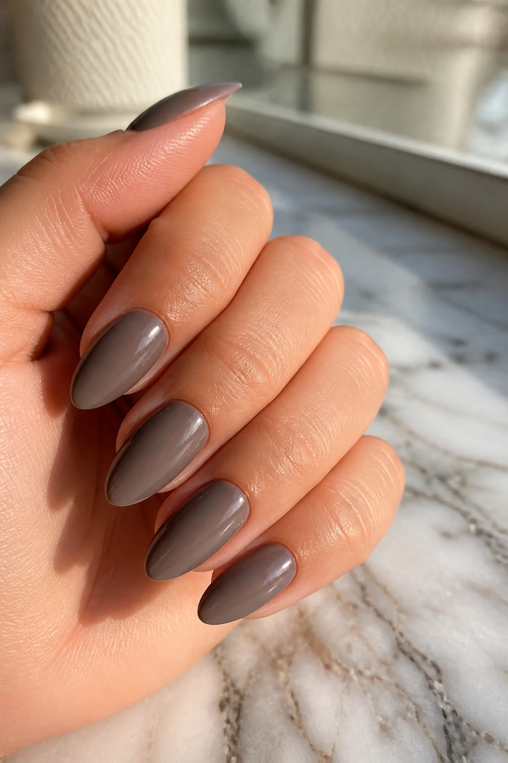 Close-up of smoky mushroom almond nails on a real hand with soft window light