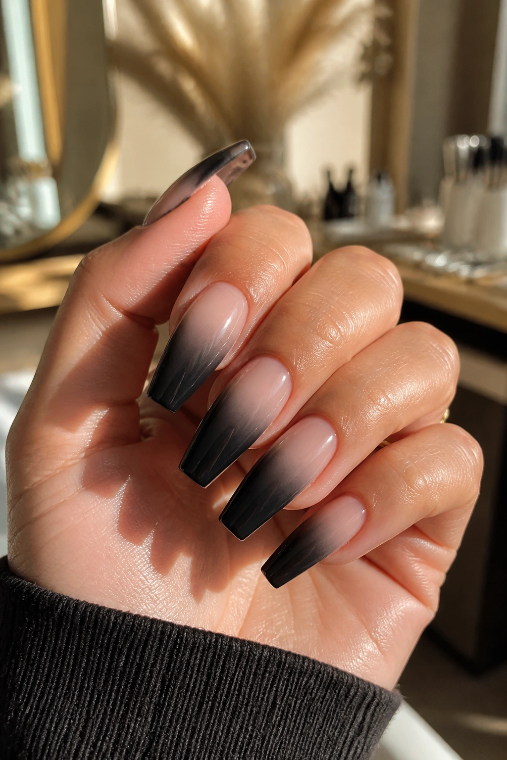 Close-up of smoky ombré coffin nails fading from nude to black on a manicured hand