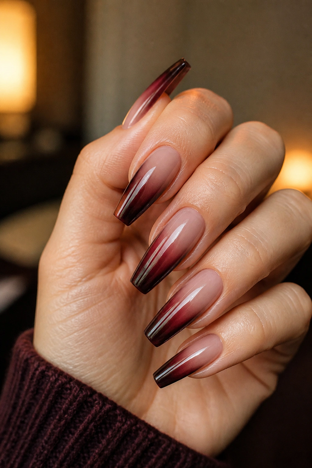 Close-up of real hand showing smoky ombre dark red French fade on coffin nails.