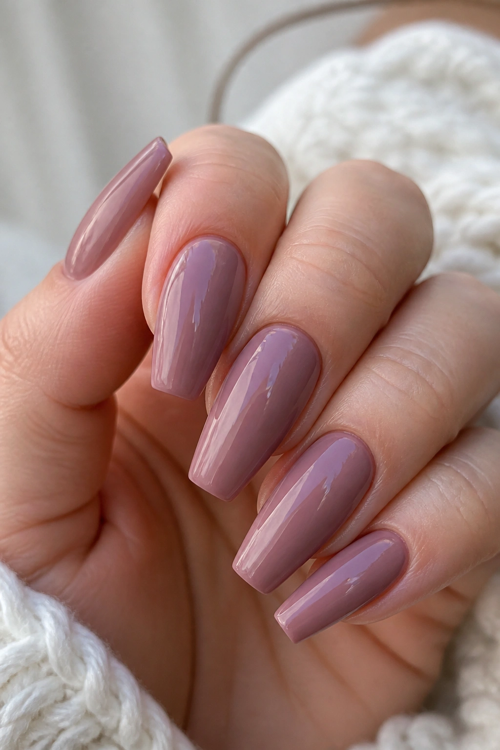 Close-up of hands with soft mauve coffin nails on a real person in warm light