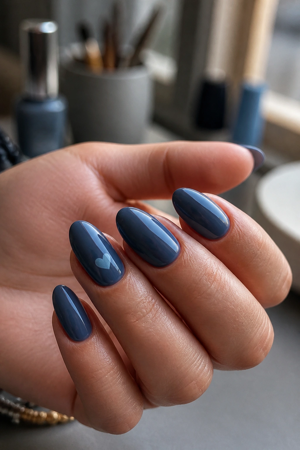 Close-up of an almond nail with storm blue base and a tiny heart accent on a ring finger