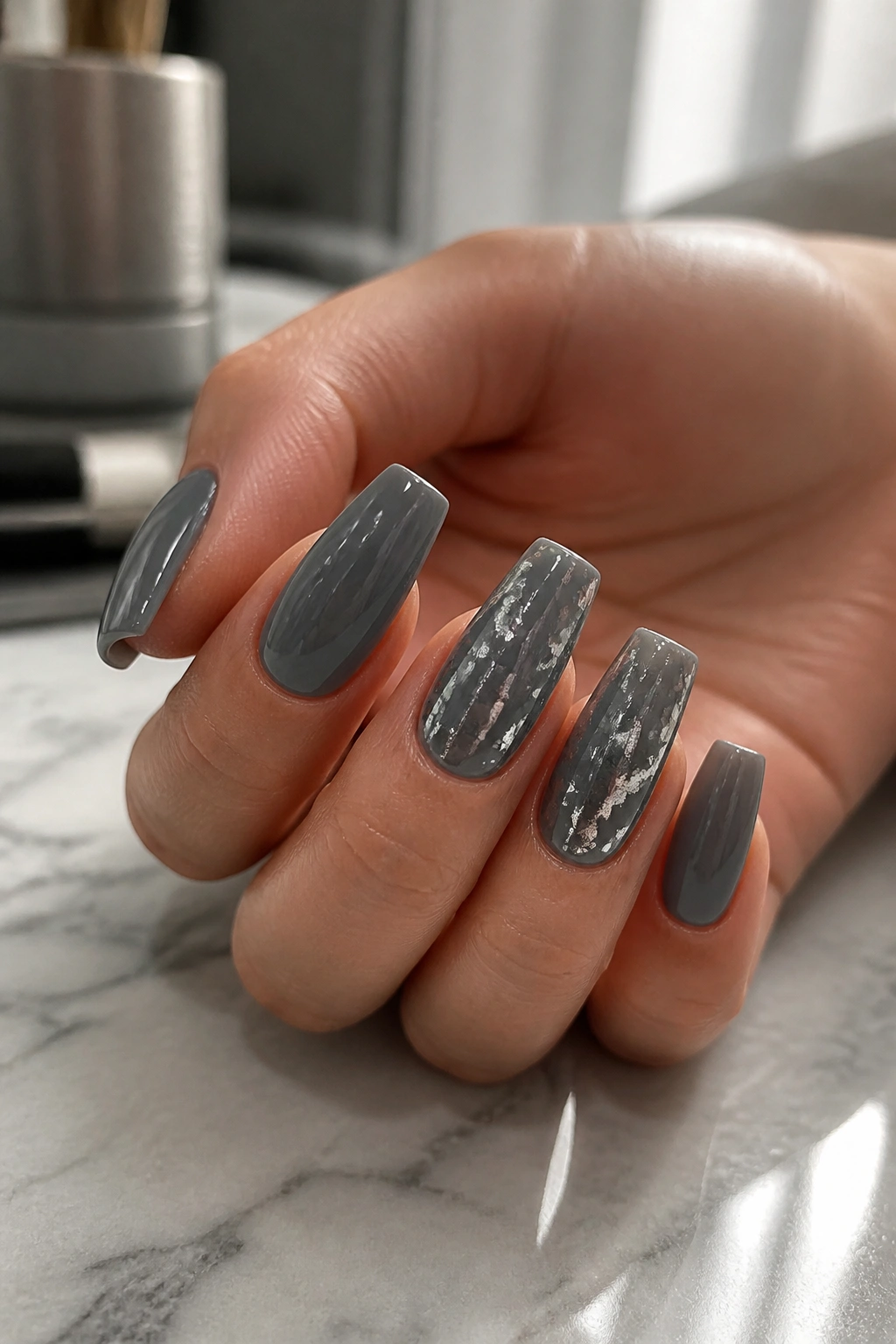 Close-up of storm grey nails with scattered silver foil accents.