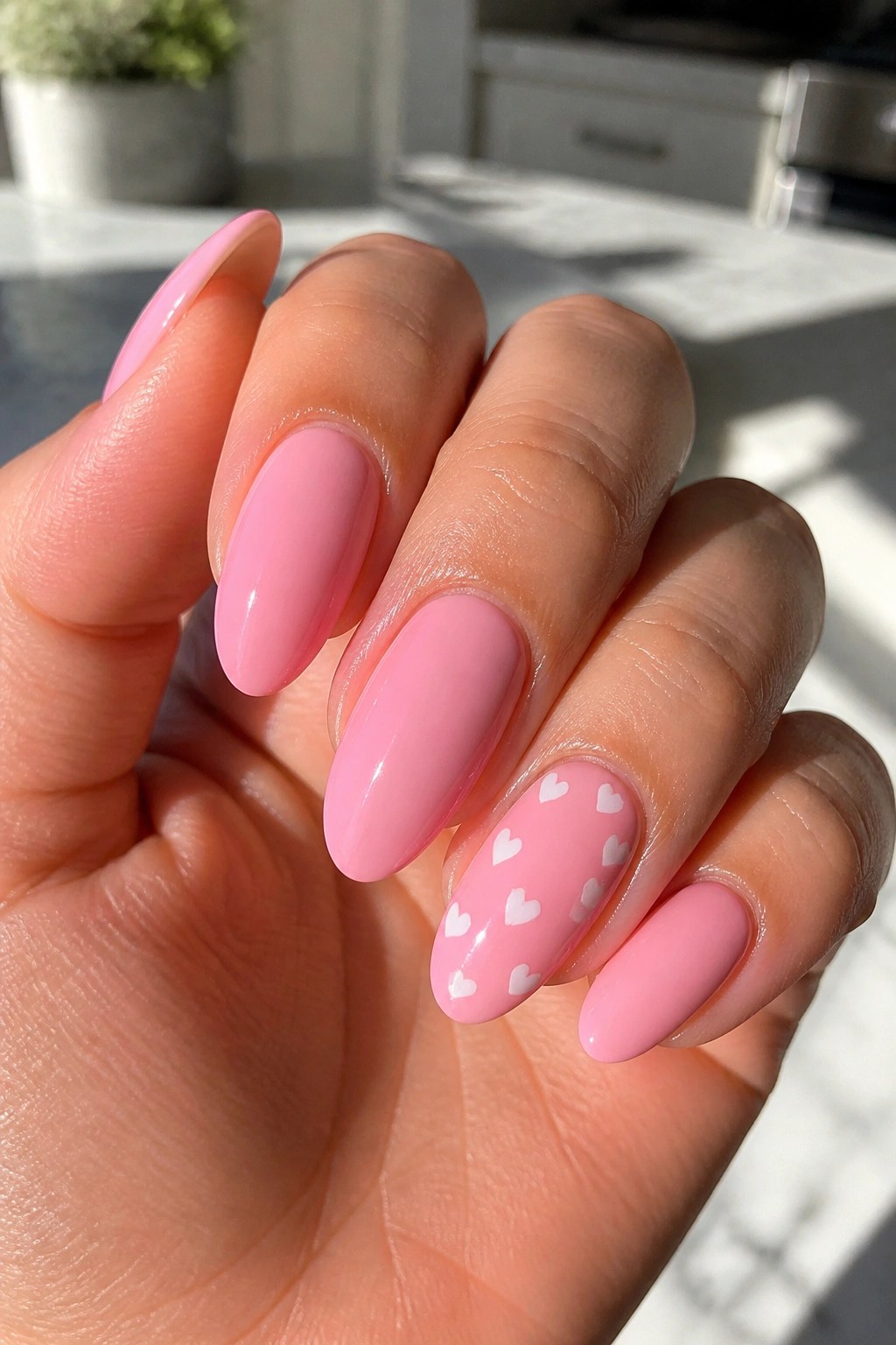 Close-up of strawberry milk pink nails with tiny white hearts on a real hand.