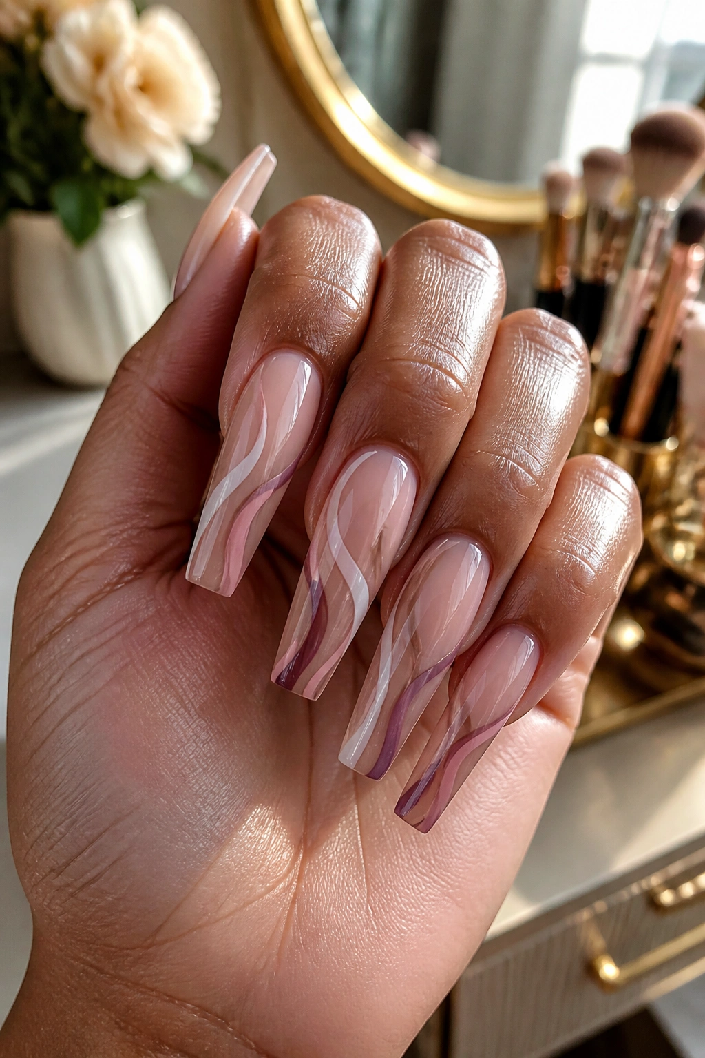 Close-up of a hand with swirl coffin nails on tapered shape in warm vanity light