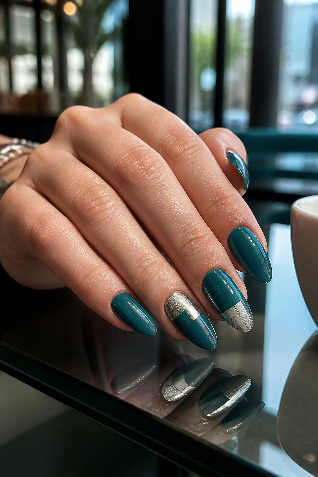 Close-up of teal nails with silver geometric blocks on accent nails, almond shape