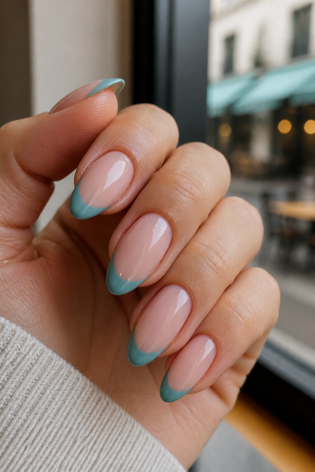 Almond nails with teal-tinted French tips on a real hand